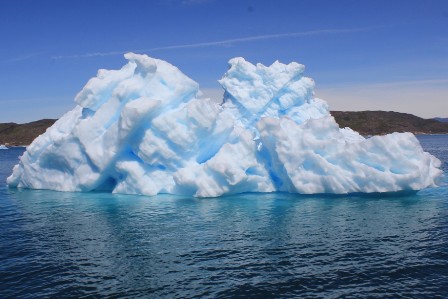 an iceberg and the trail of a plane in the sky