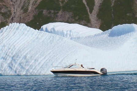 A small private boat saling near an iceberg