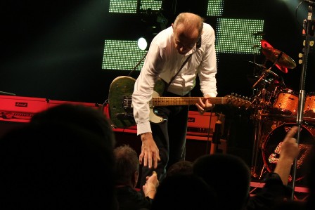 Francis Rossi giving a Status Quo guitar pick to a fan on the first row